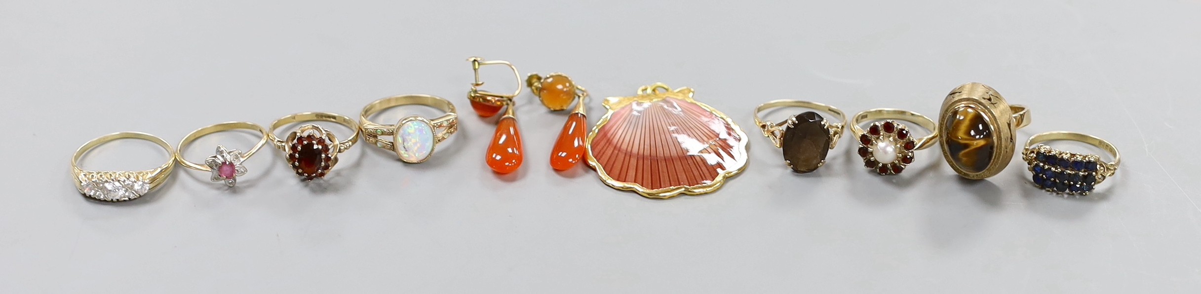 Eight assorted modern 9ct gold and gem set dress rings, a pair of 9ct and carnelian set drop earrings, gross weight 30.7 grams. and a yellow metal mounted shell pendant.